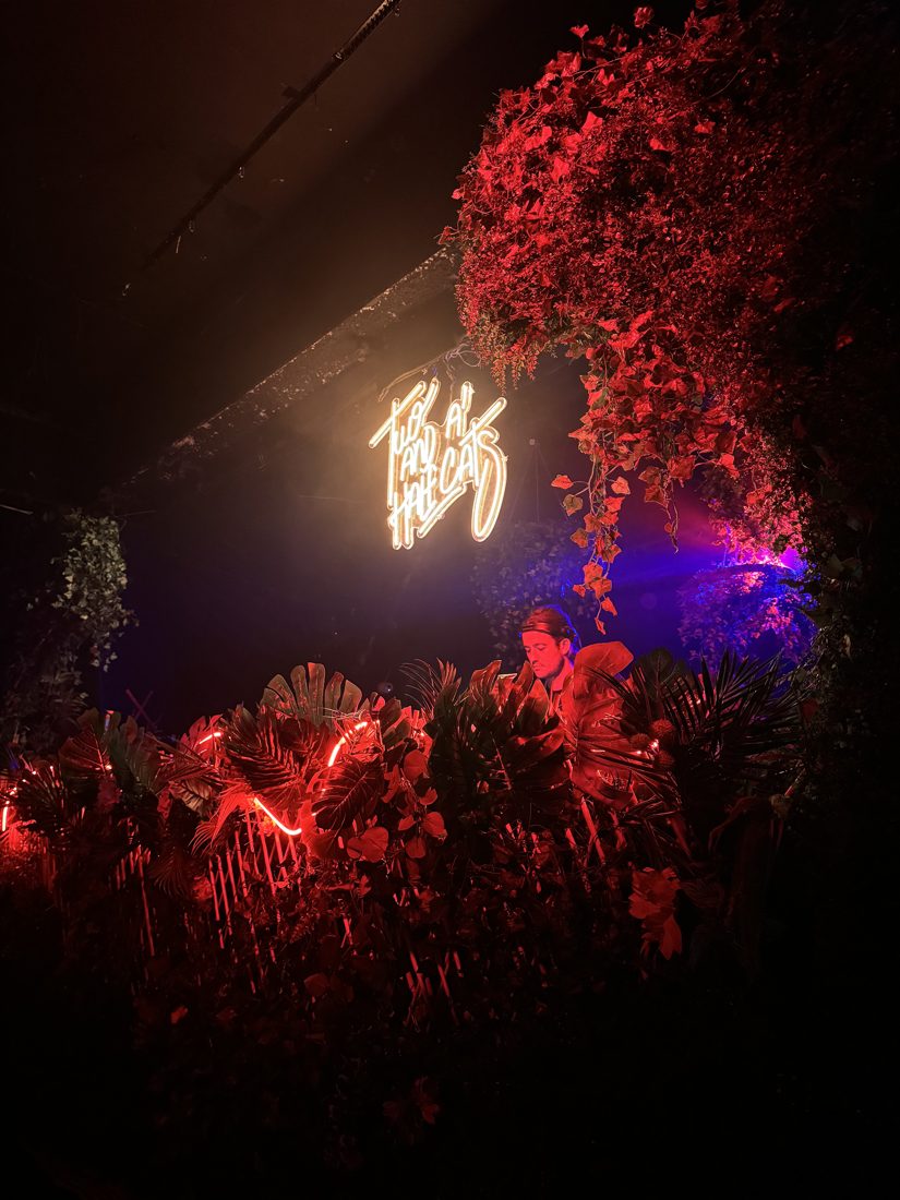 DJ booth wrapped in red florals with a neon sign